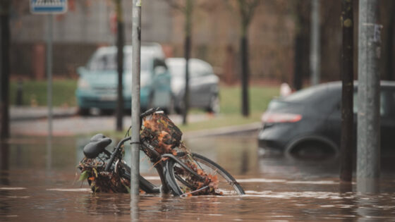 Cykel och bilar halvt under vatten på översvämmad gata