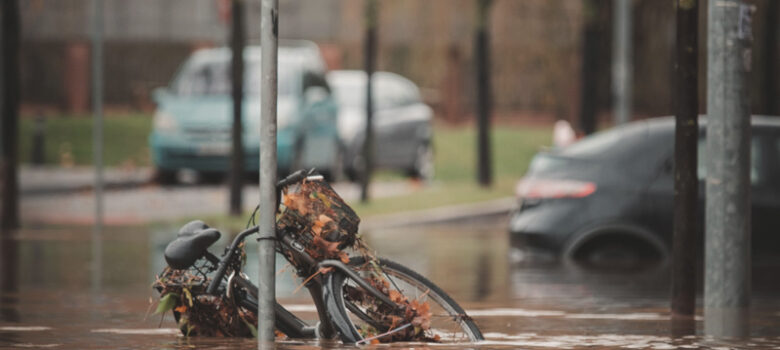 Cykel och bilar halvt under vatten på översvämmad gata