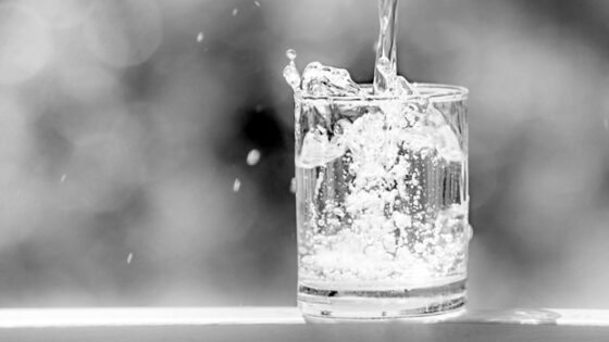 svartvitt fotografi av vatten som hälls i ett glas
